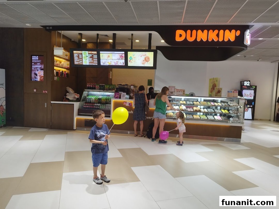 Customers browse delicious donuts and beverages at the vibrant Dunkin' Donuts counter.