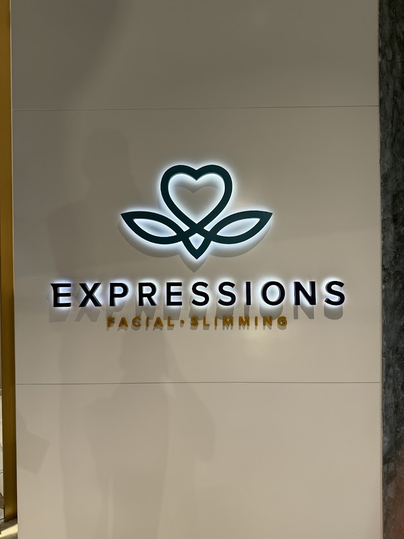 Close-up of the Expressions shop logo and name on a white wall.