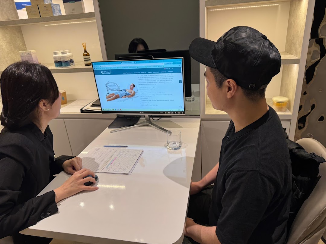 A staff member consults with a customer, showcasing slimming solutions on a computer screen.