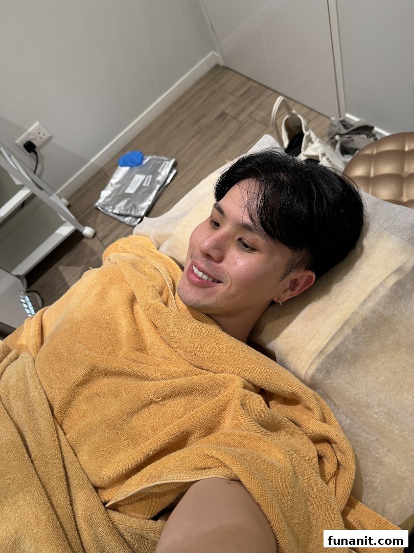 A man in a yellow towel smiles while relaxing on a treatment bed at Expressions Funan.