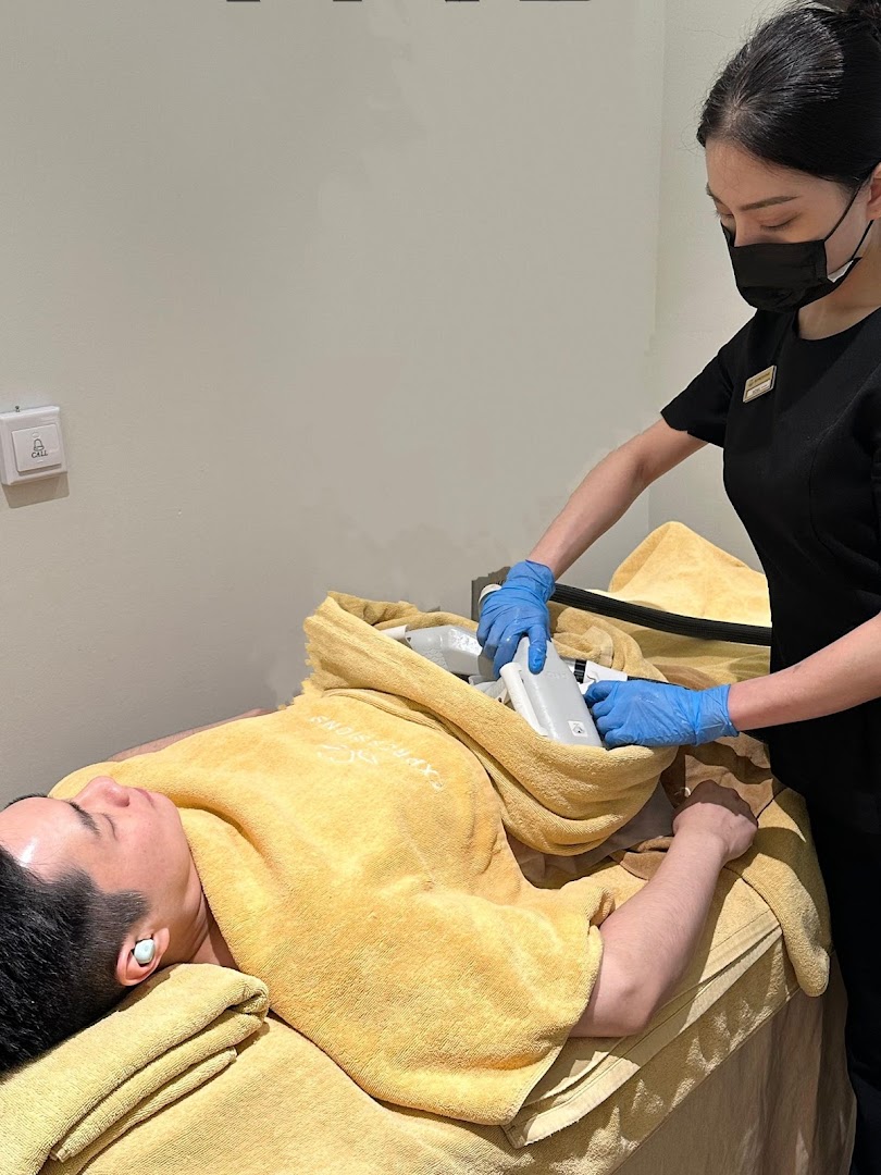 A staff member performs a body slimming treatment on a male client at Expressions Funan.