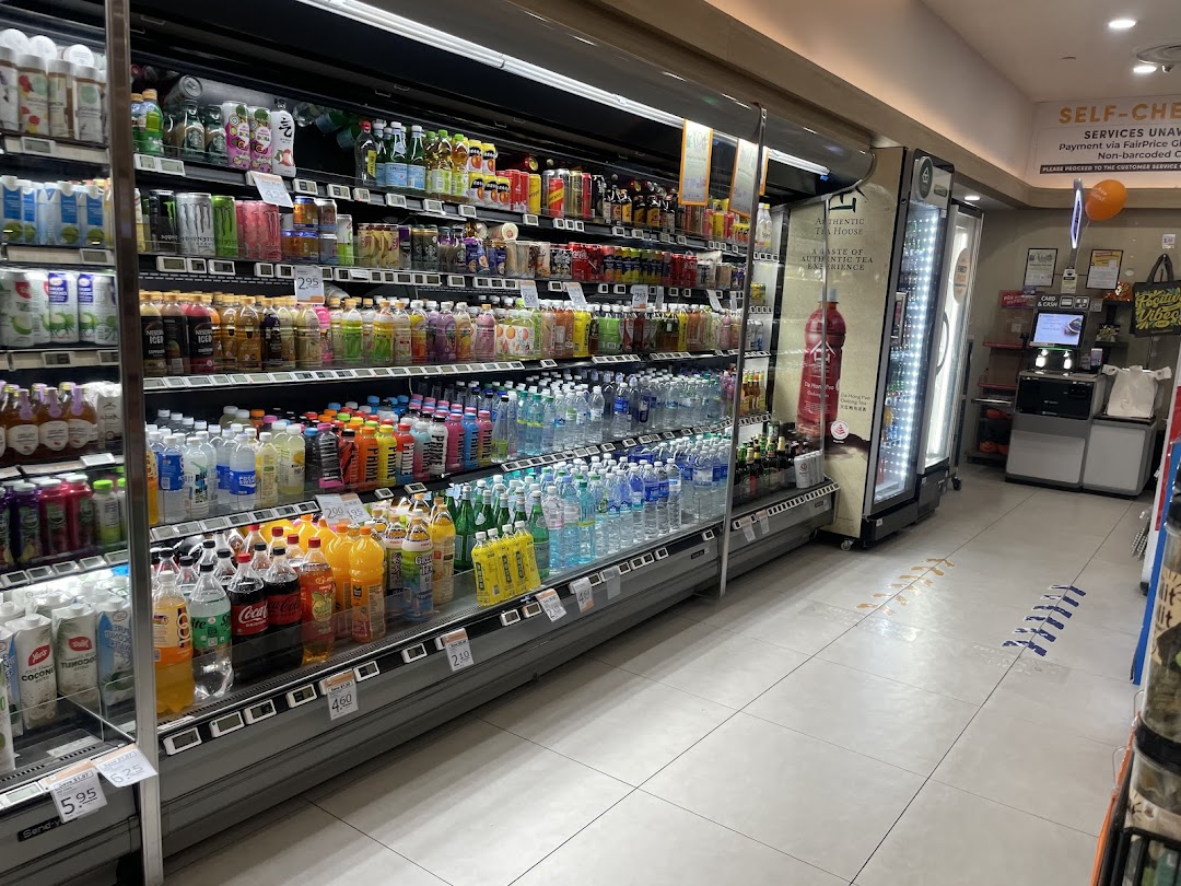 A well-stocked aisle of chilled beverages and drinks at FairPrice Finest, with a self-checkout area.