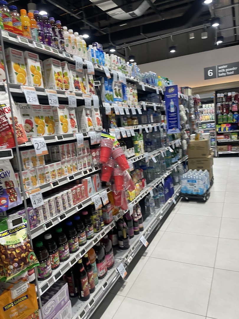 An aisle inside FairPrice Finest Funan Mall, stocked with a variety of beverages and snacks.