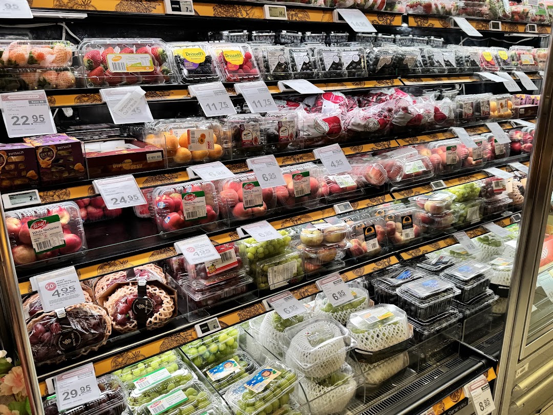 A well-stocked display of fresh, packaged fruits and berries in a supermarket aisle.