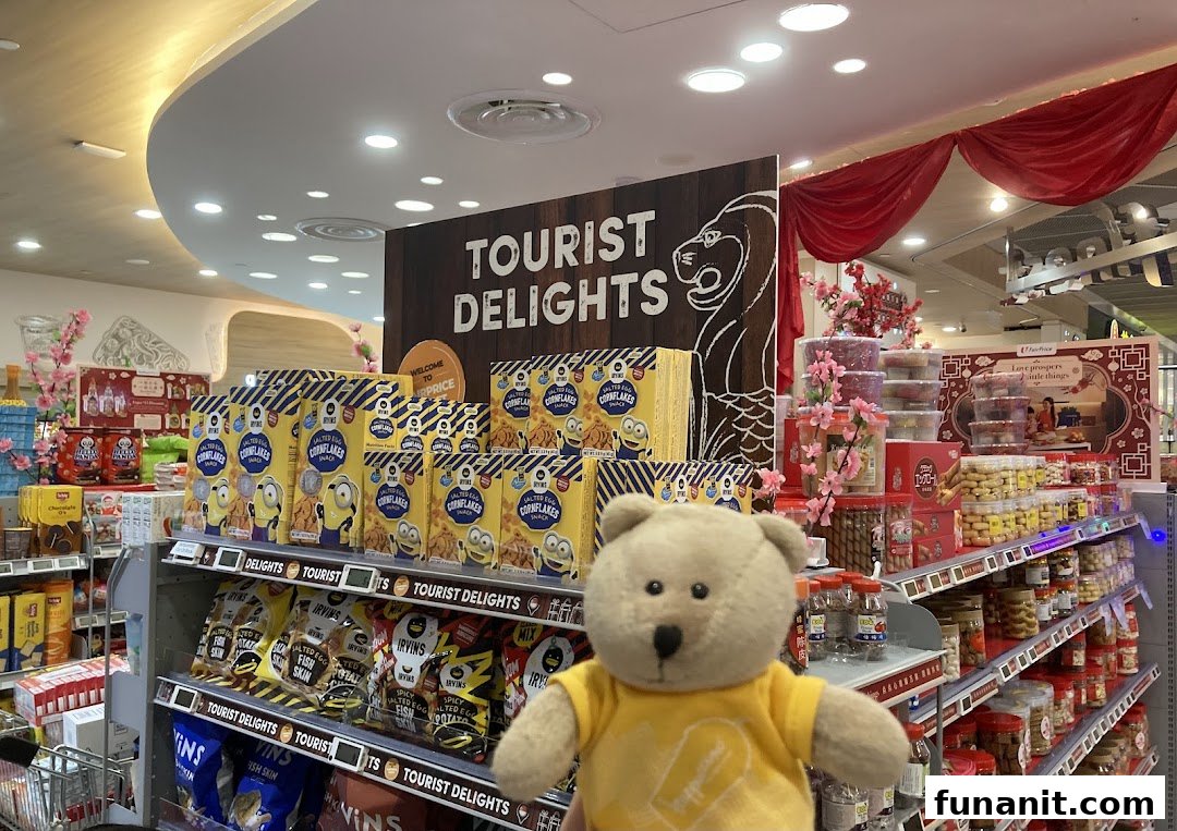 A supermarket aisle featuring 'Tourist Delights' products, including snacks and local specialties, with a teddy bear in the foreground.
