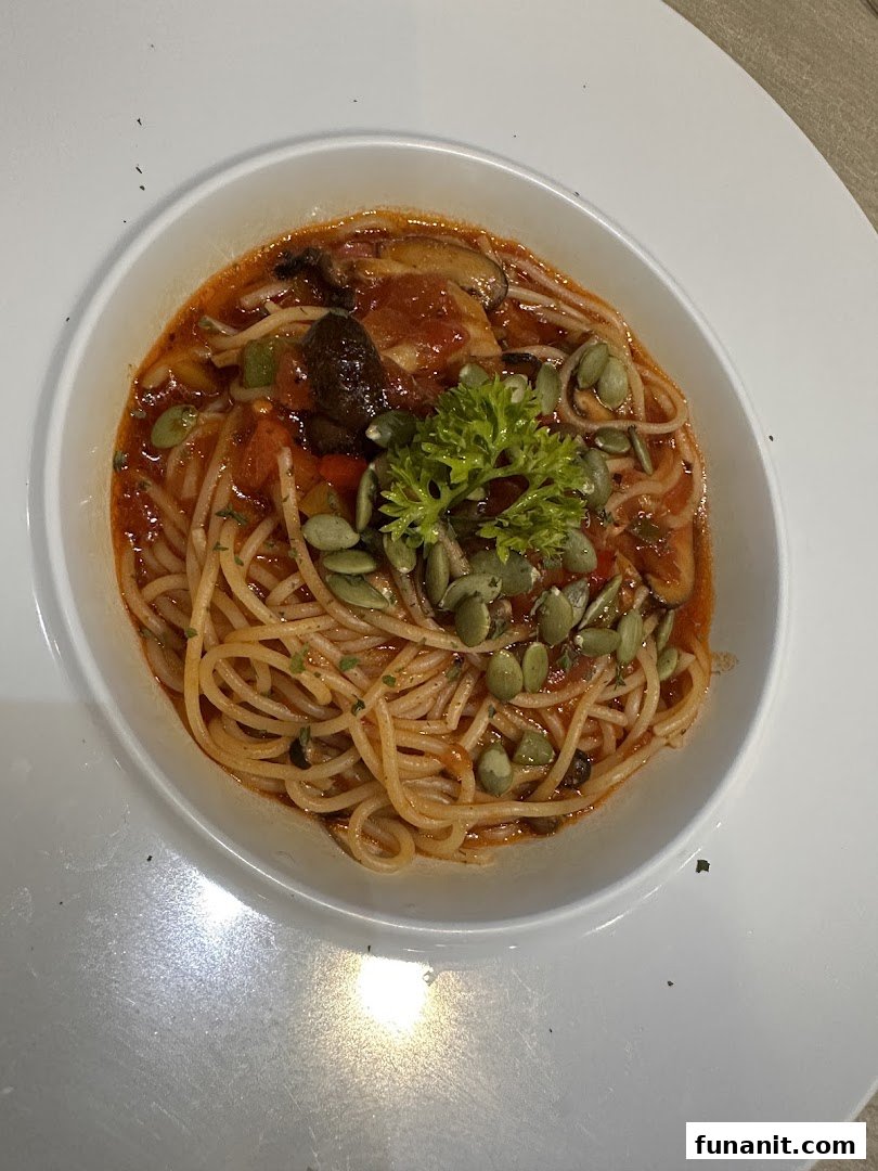 A vibrant bowl of spaghetti with tomato sauce, mushrooms, vegetables, and pumpkin seeds.
