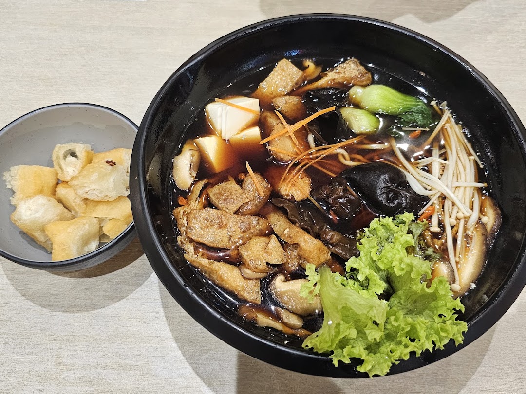 A rich, dark broth soup with assorted mushrooms, tofu, vegetables, and a side of crispy fried dough.