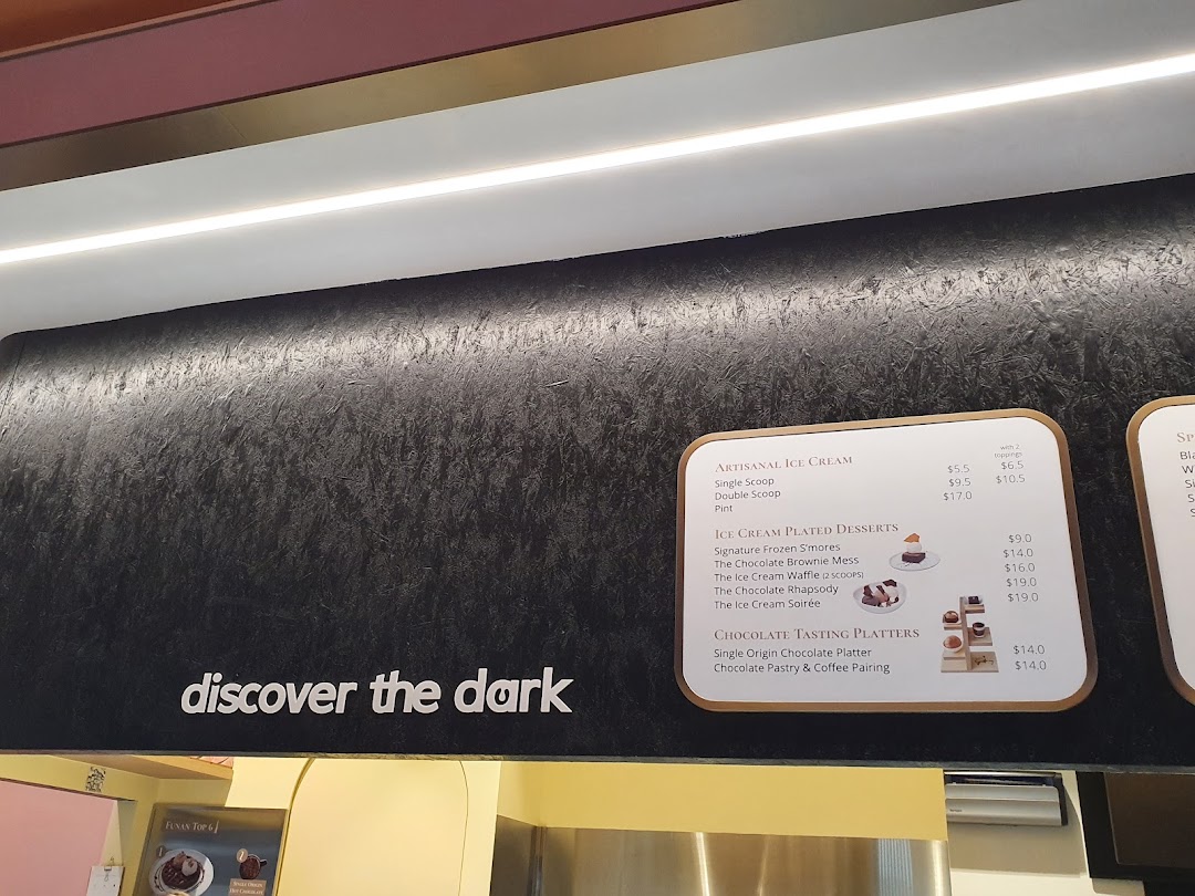 A menu board displaying artisanal ice cream, plated desserts, and chocolate tasting platters with prices.