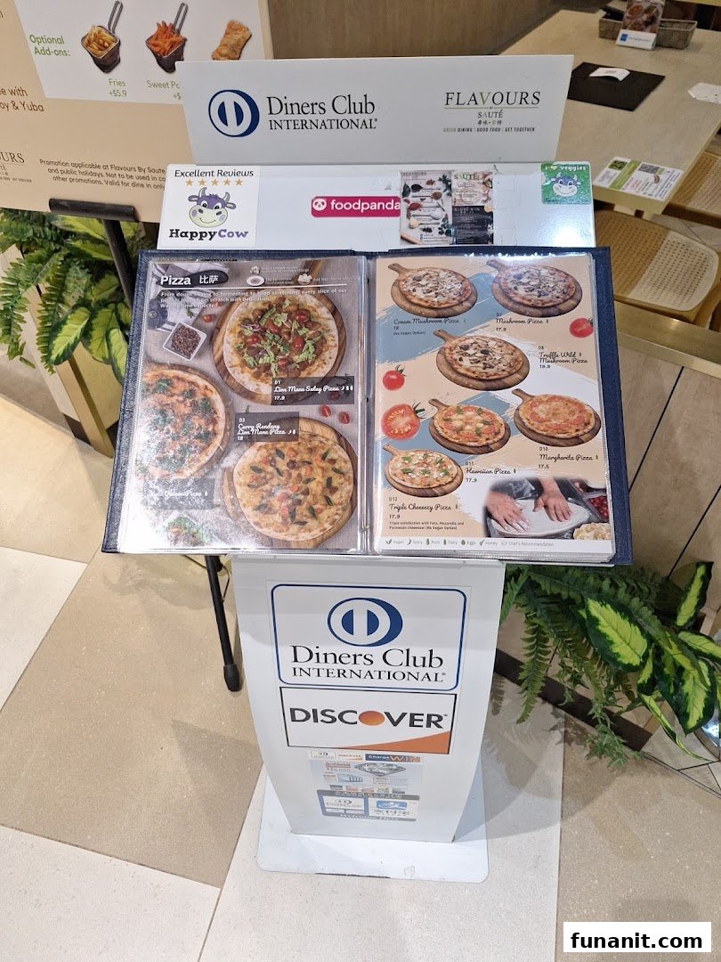 A menu stand displaying various vegetarian and vegan pizza options from Flavours by Saute.
