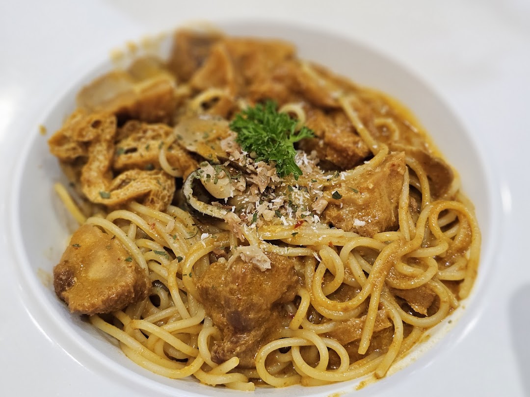 A close-up of a delicious pasta dish with a rich, creamy sauce, topped with tofu puffs and herbs.