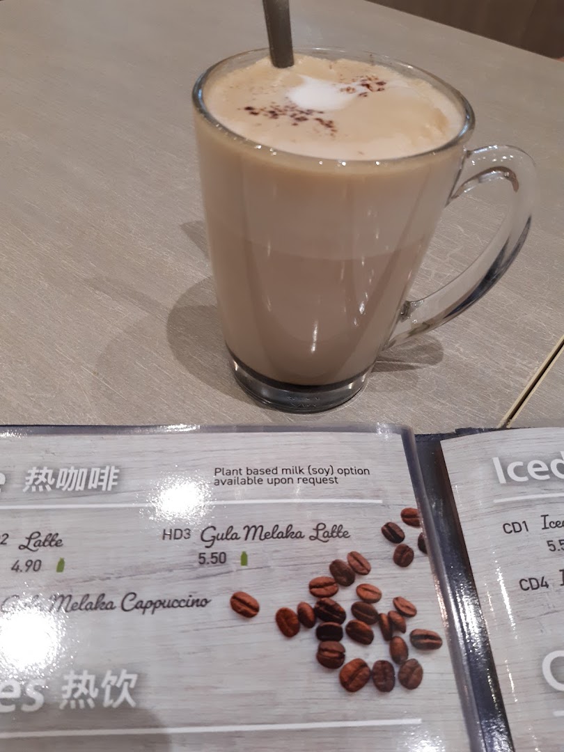 A close-up of a menu displaying hot and iced drink options, with a Gula Melaka Latte in the foreground.