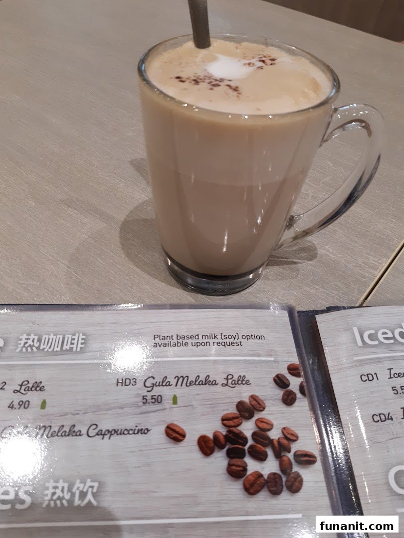 A close-up of a menu displaying hot and iced drink options, with a Gula Melaka Latte in the foreground.