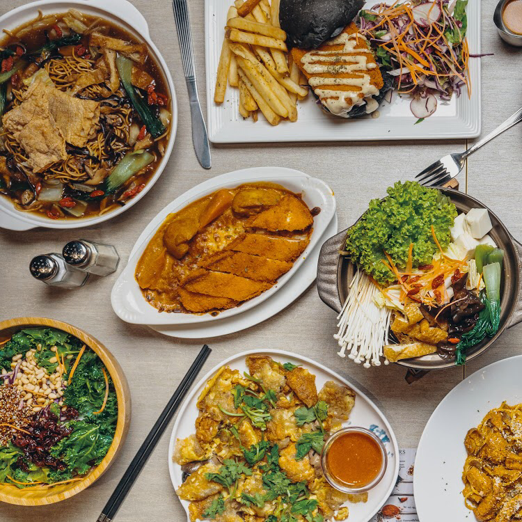 A vibrant spread of diverse vegetarian and vegan dishes, showcasing local and Western fusion cuisines.
