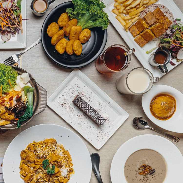 An overhead view of a table laden with a variety of delicious vegetarian and vegan dishes, drinks, and desserts.