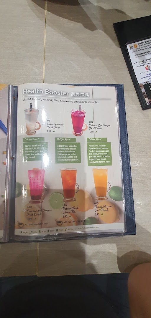 A menu page displaying a selection of vibrant 'Health Booster' fruit drinks with their prices and health benefits.