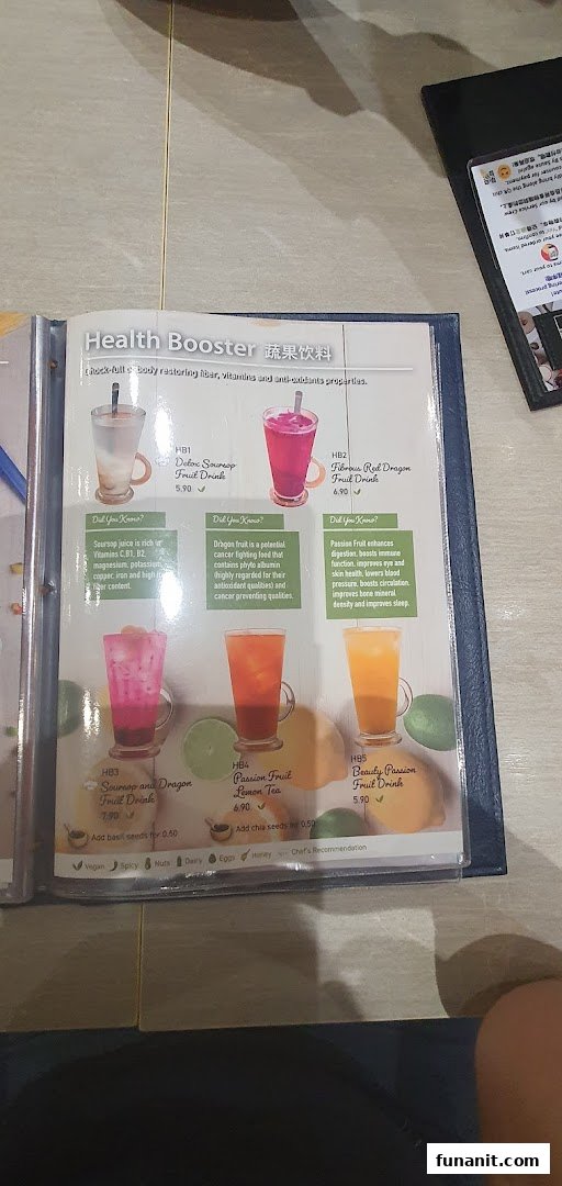 A menu page displaying a selection of vibrant 'Health Booster' fruit drinks with their prices and health benefits.