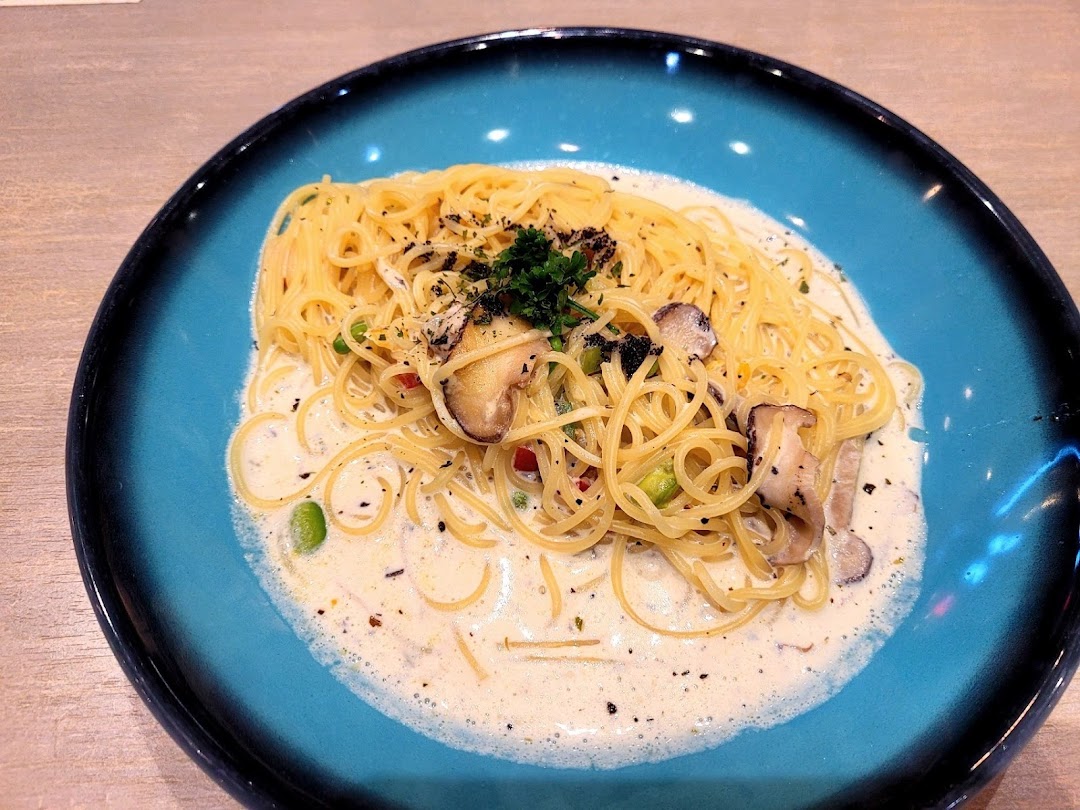 A close-up of creamy pasta with mushrooms, peas, and herbs on a vibrant blue plate.