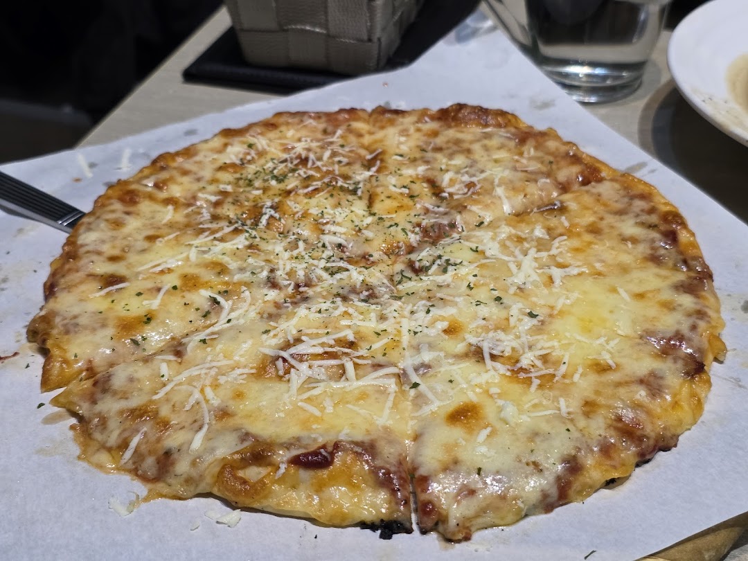 A freshly baked, cheesy pizza topped with herbs, served on parchment paper.