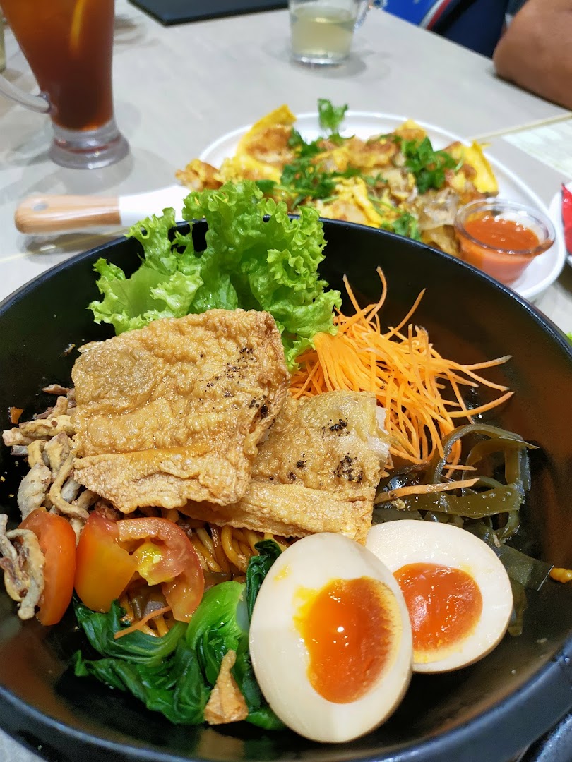 A vibrant bowl of vegetarian noodles with crispy beancurd, vegetables, and a soft-boiled egg.