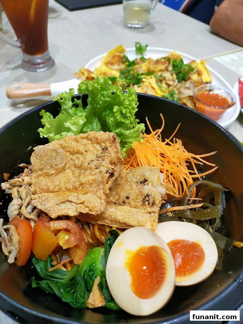A vibrant bowl of vegetarian noodles with crispy beancurd, vegetables, and a soft-boiled egg.