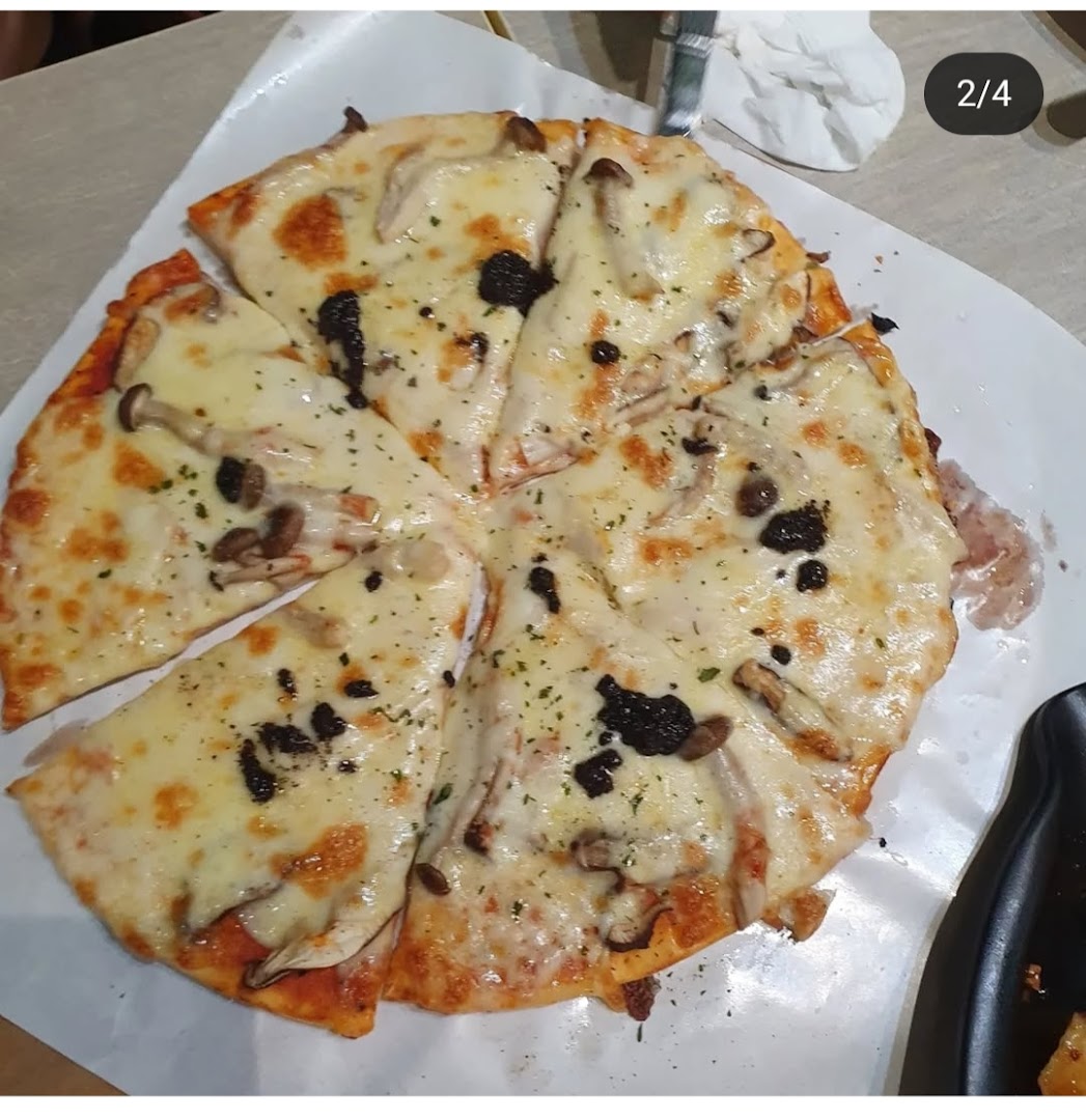 A delicious mushroom and cheese pizza with truffle shavings, served on white paper.