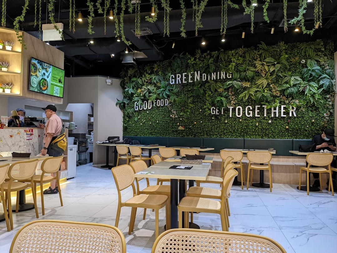Vibrant interior of Flavours by Saute, featuring a lush green wall, modern dining tables, and a service counter.