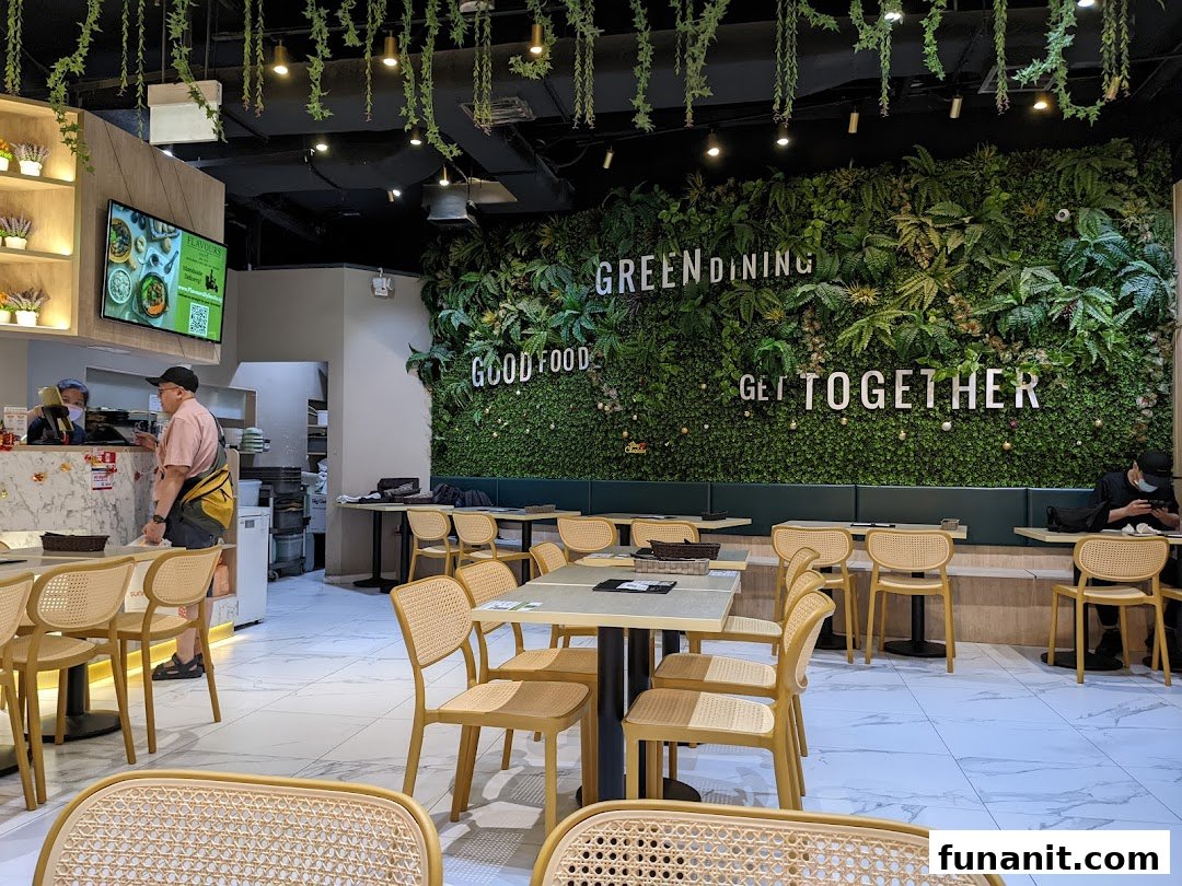 Vibrant interior of Flavours by Saute, featuring a lush green wall, modern dining tables, and a service counter.