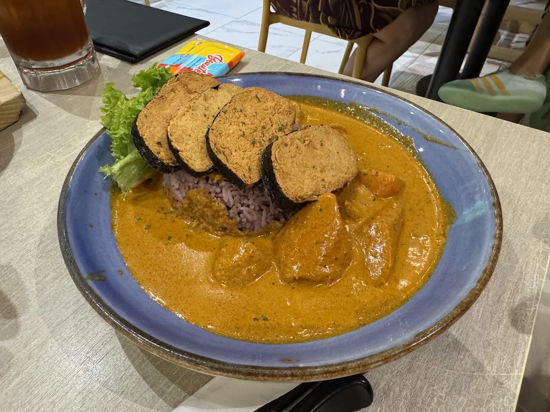 A vibrant plate of vegetarian curry with purple rice and crispy fried items, served at Flavours by Saute.