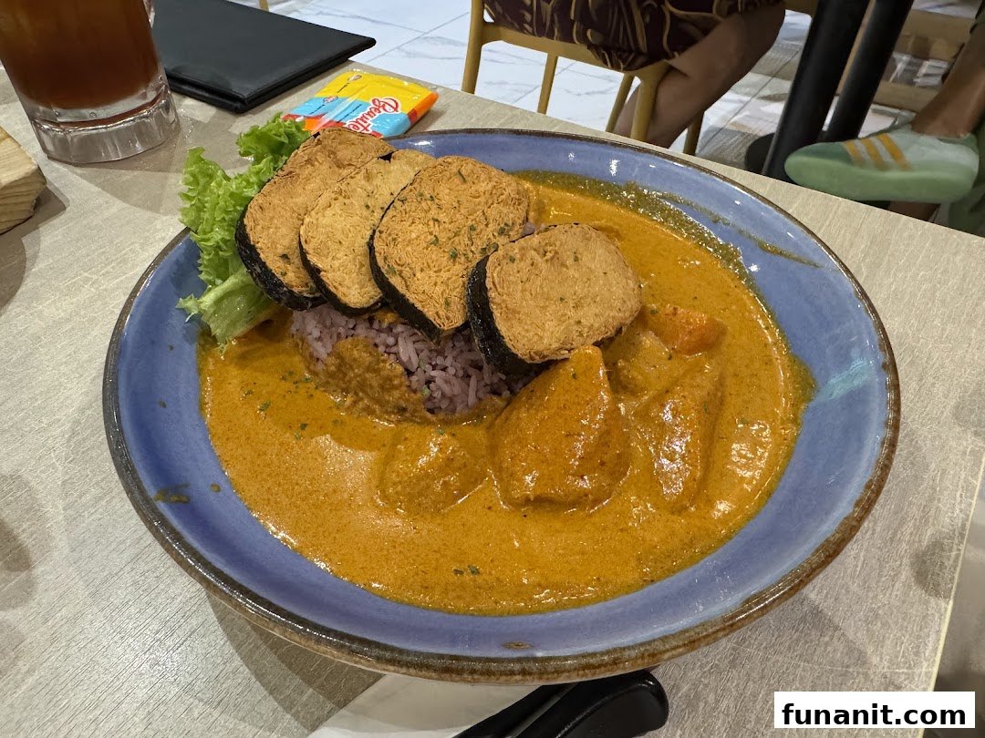 A vibrant plate of vegetarian curry with purple rice and crispy fried items, served at Flavours by Saute.