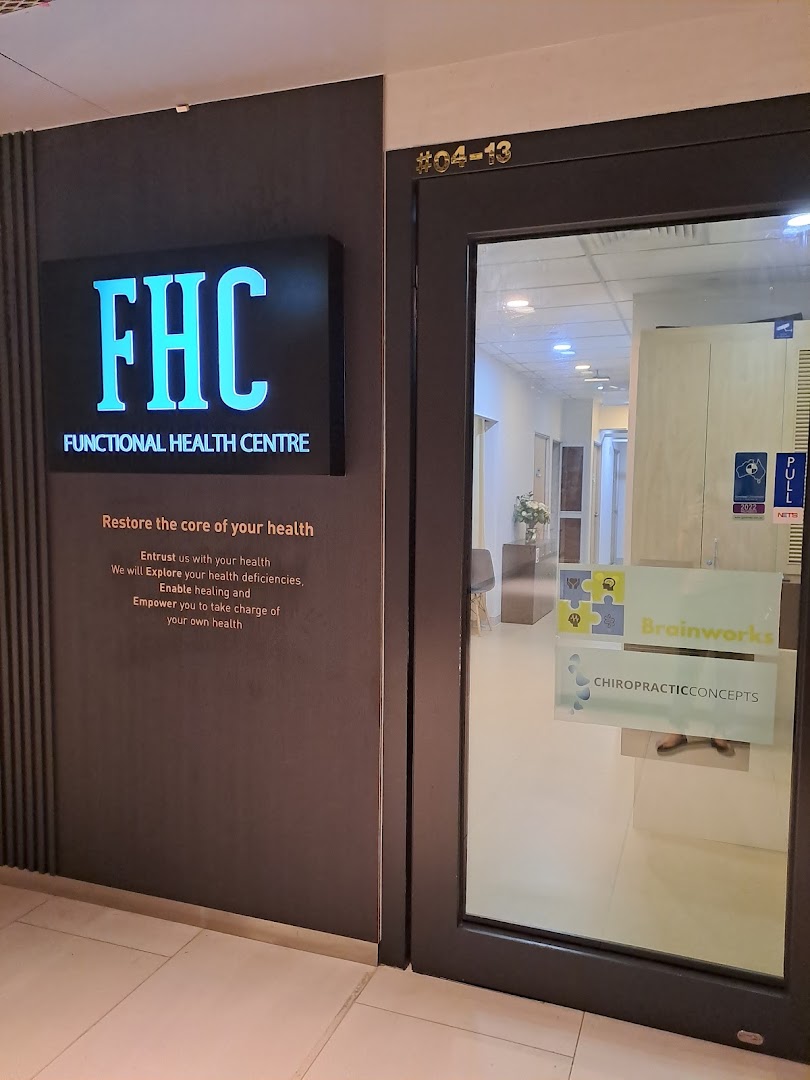The image displays the modern entrance of Functional Health Centre (FHC) with its illuminated sign and glass door.