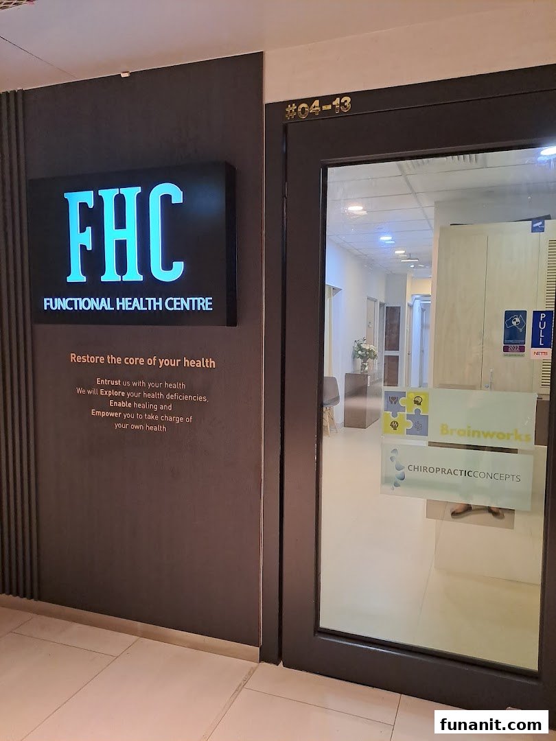 The image displays the modern entrance of Functional Health Centre (FHC) with its illuminated sign and glass door.