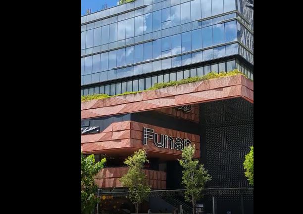 The modern exterior of Funan mall, featuring glass facades, green roofs, and distinctive brickwork.
