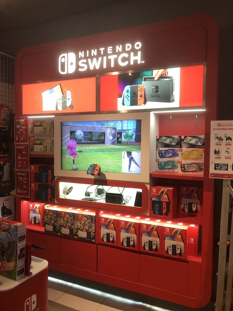 A vibrant red Nintendo Switch display showcasing consoles, games, and accessories in a retail store.