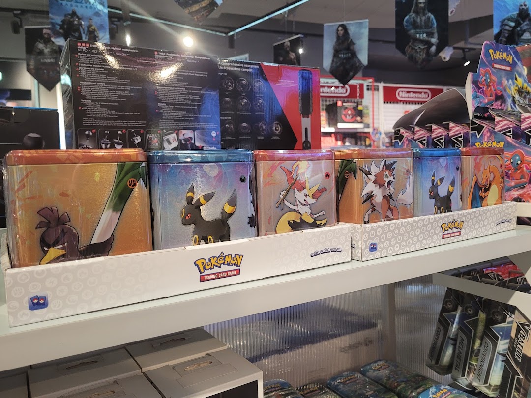 A shelf displays various Pokémon Trading Card Game tins and other gaming merchandise inside GameMartz.