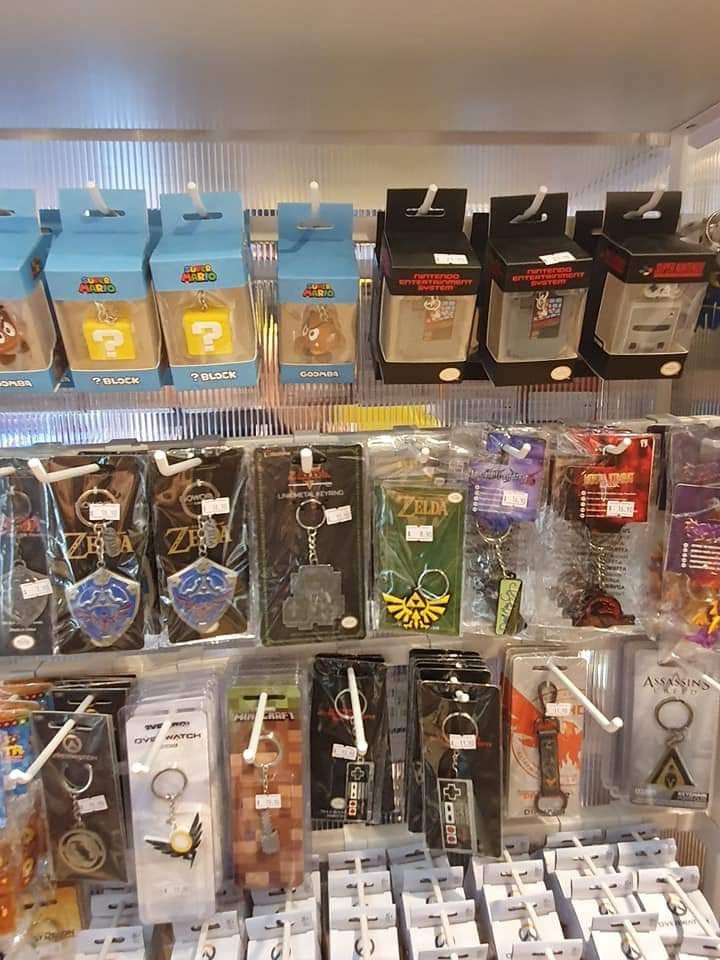A display of gaming-themed keychains and collectibles, including Super Mario, Zelda, and retro console designs.