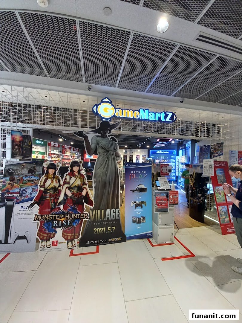 The shop front of GameMartz, featuring video game displays, promotional cutouts for Monster Hunter Rise and Resident Evil Village.