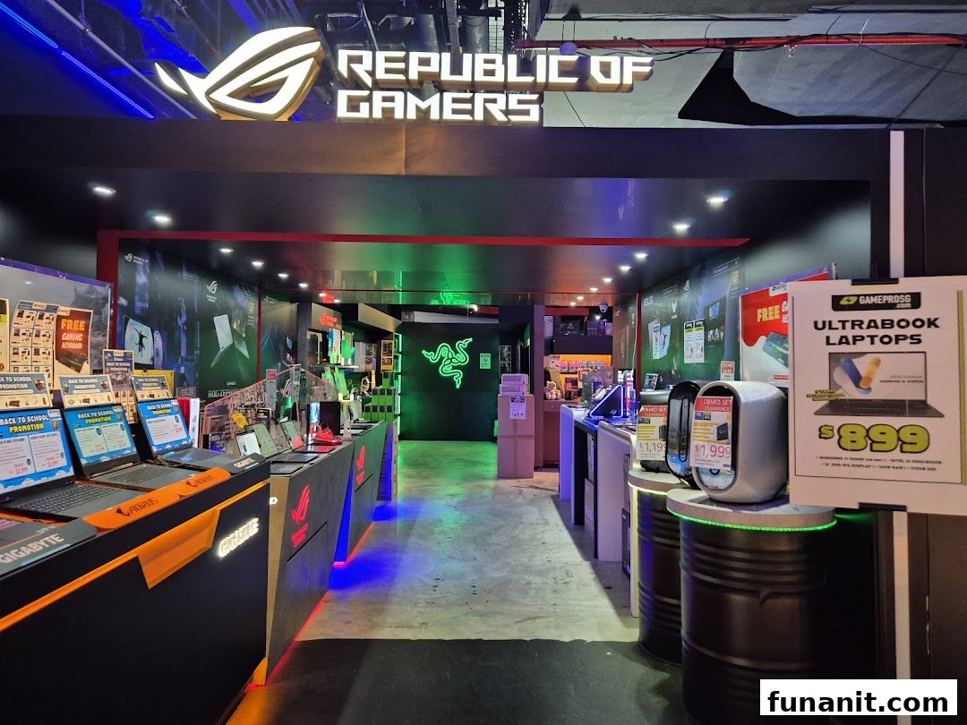 Illuminated entrance of GAMEPROSG, a gaming and laptop store, showcasing various tech displays.