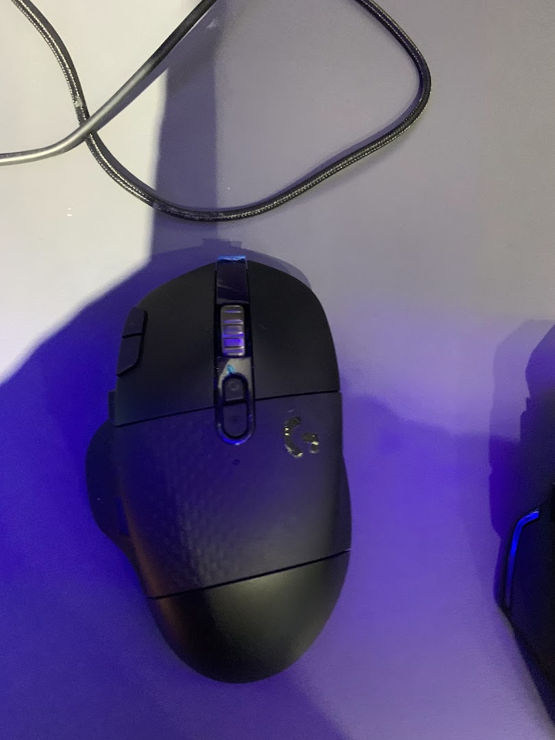 A close-up of a black Logitech gaming mouse on a surface with a cable.