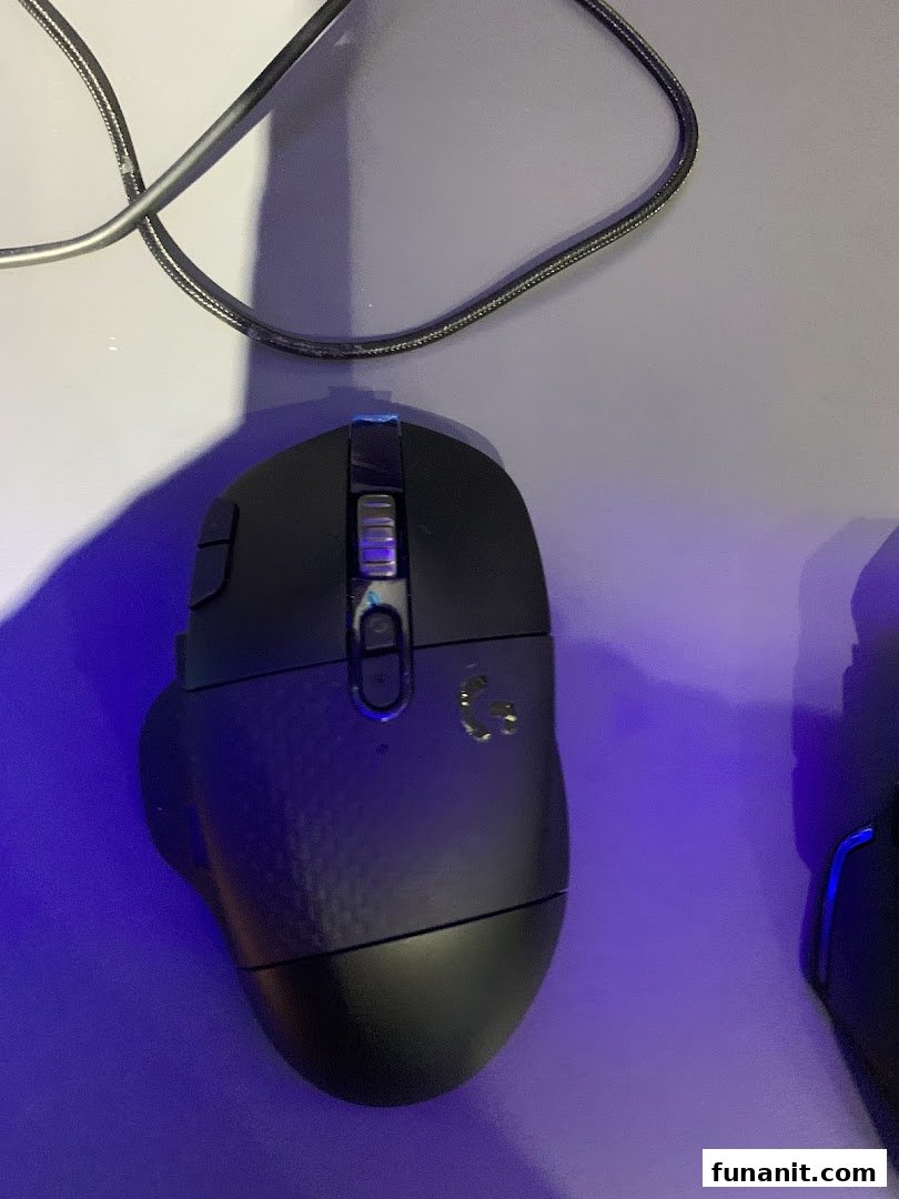 A close-up of a black Logitech gaming mouse on a surface with a cable.