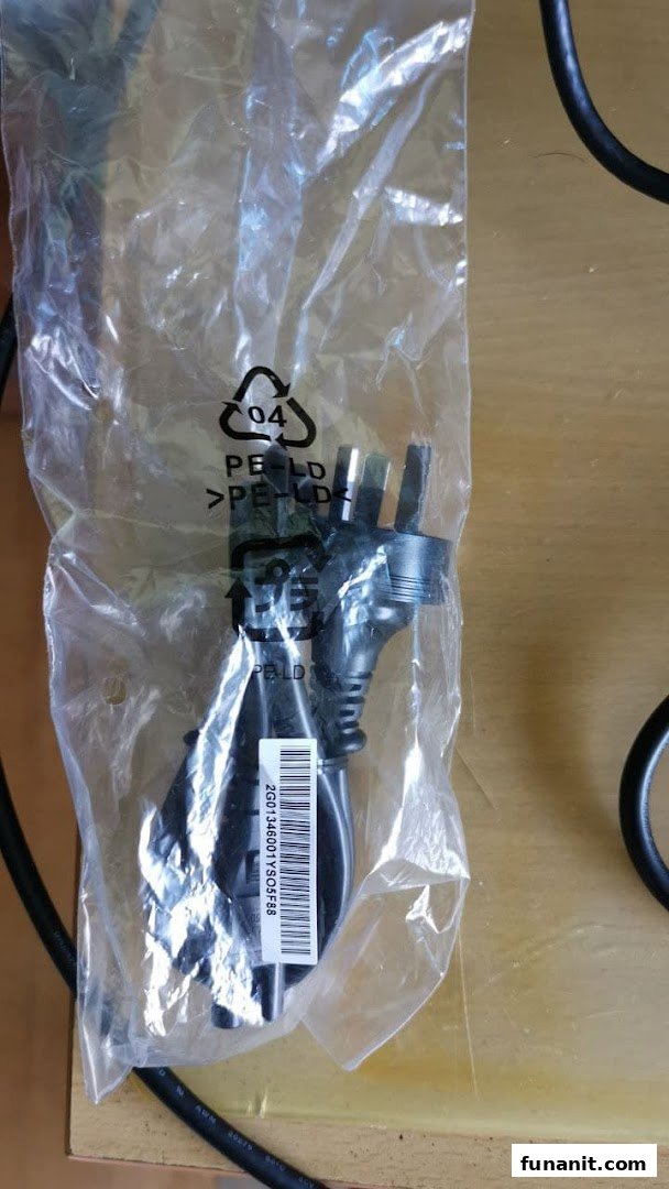 A black power cable with a UK plug, packaged in a clear plastic bag, likely an accessory.