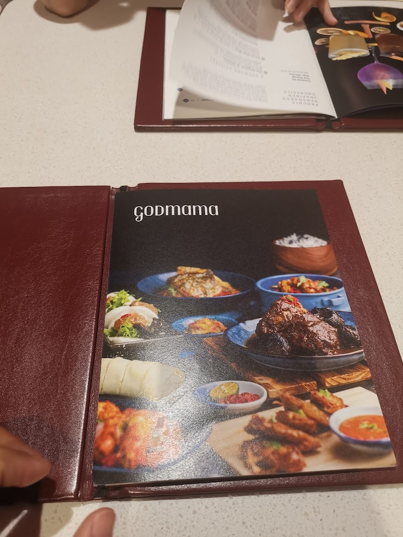 A close-up of the Godmama restaurant menu cover featuring various Peranakan dishes.