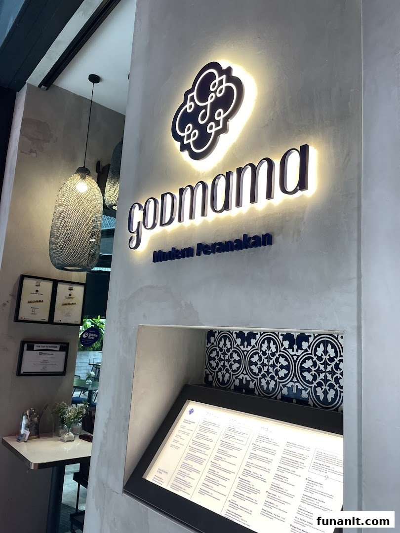 The illuminated Godmama sign and an external menu display at the entrance of the Modern Peranakan restaurant.