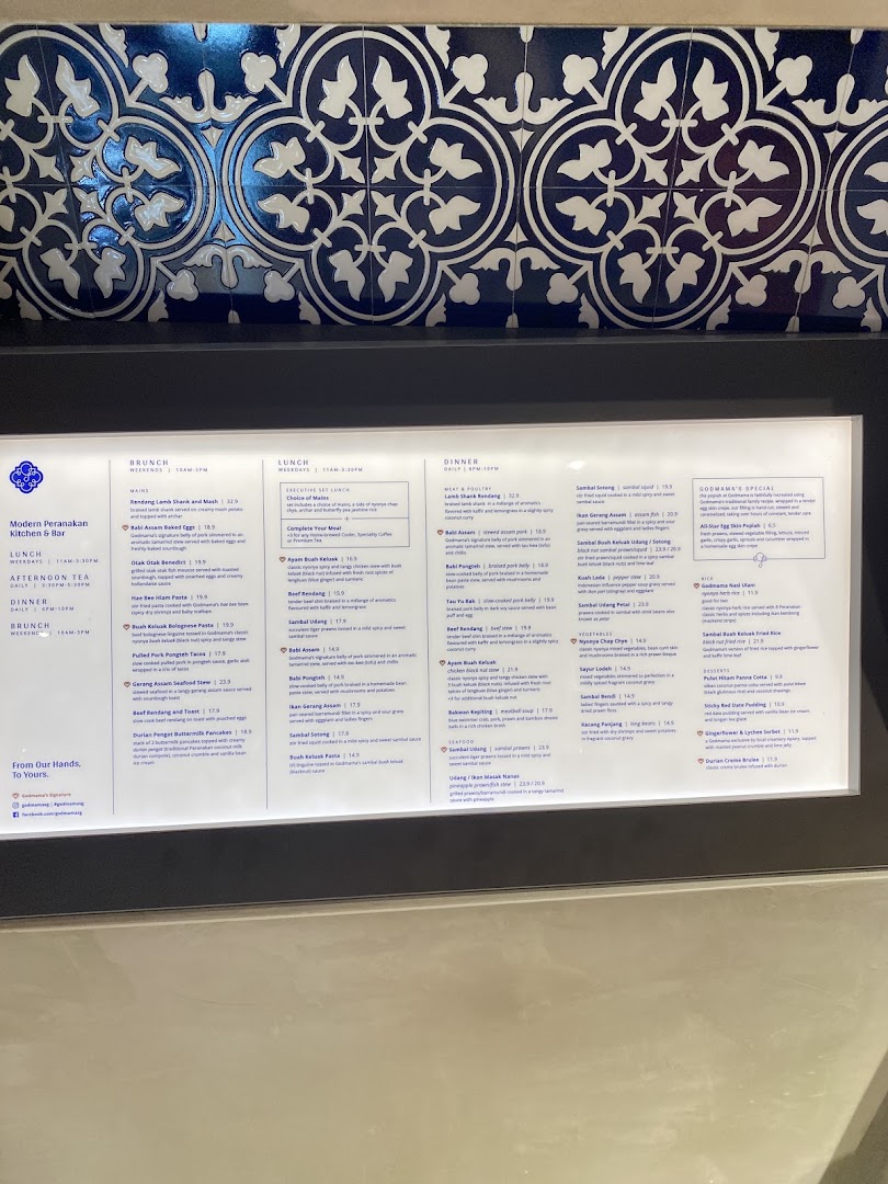 A detailed menu board for Godmama, a Modern Peranakan Restaurant, showcasing brunch, lunch, and dinner offerings.