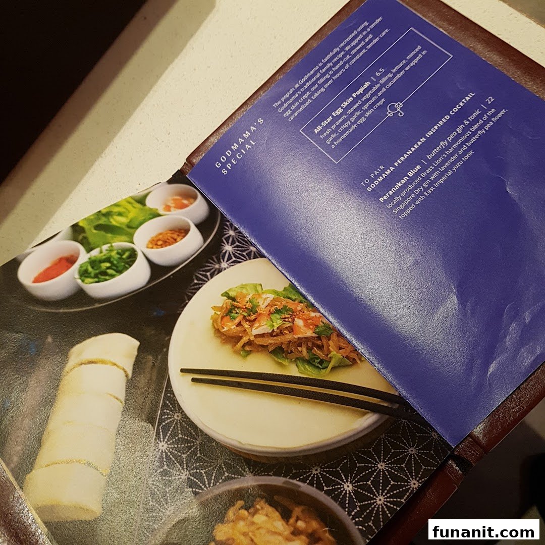 A close-up of Godmama's menu, showcasing a special popiah dish and a unique Peranakan-inspired cocktail.