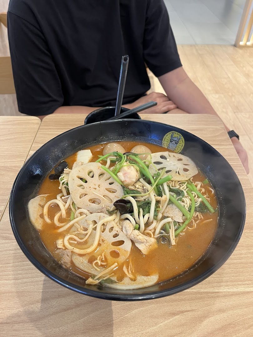 A vibrant bowl of Malatang with noodles, lotus root, vegetables, and meat, served on a wooden table.
