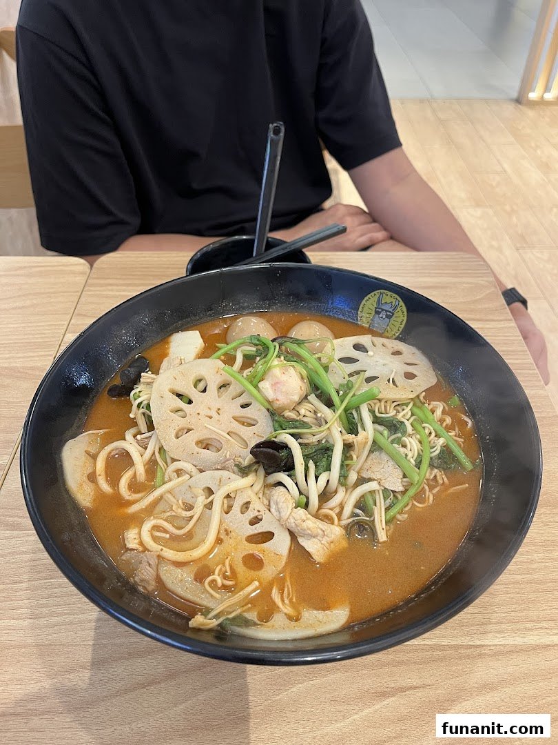 A vibrant bowl of Malatang with noodles, lotus root, vegetables, and meat, served on a wooden table.