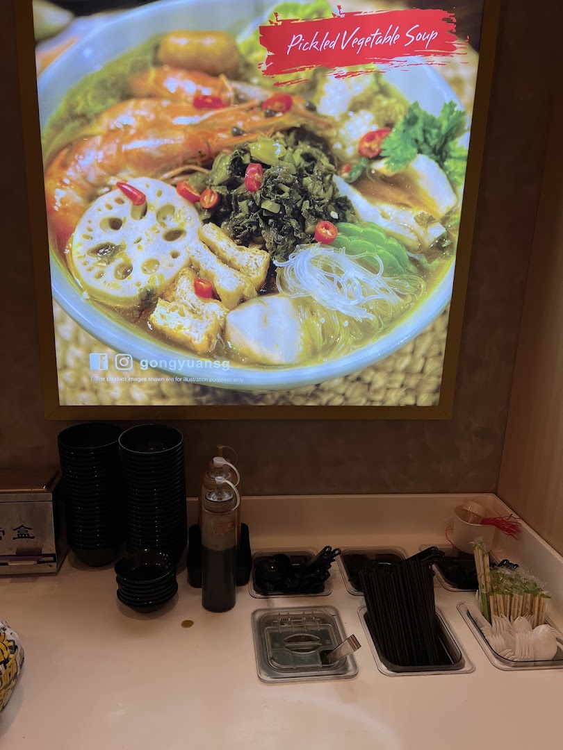 A vibrant display of Pickled Vegetable Soup above a self-service condiment and utensil station.