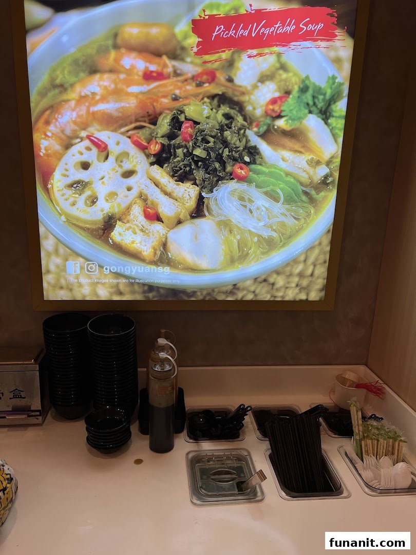 A vibrant display of Pickled Vegetable Soup above a self-service condiment and utensil station.
