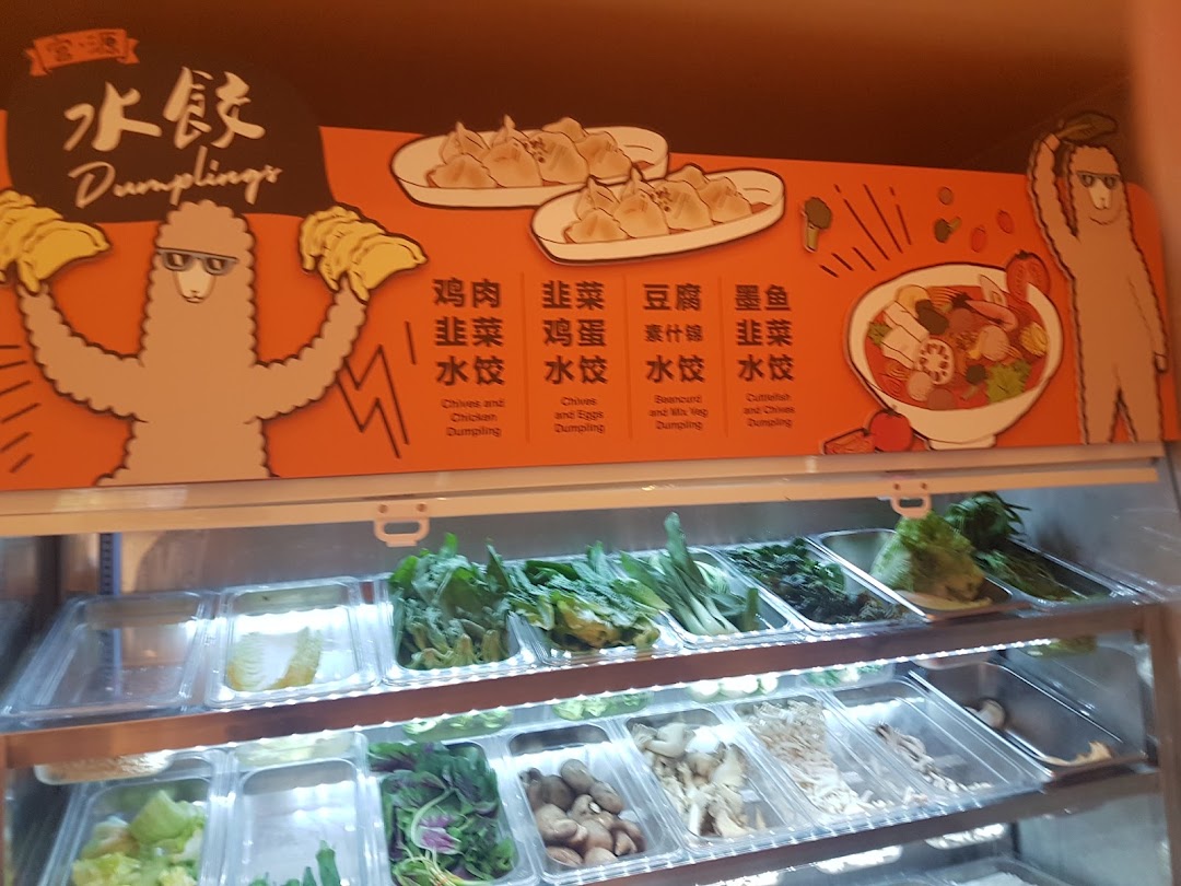 A vibrant display of fresh ingredients and a menu board showcasing various dumpling options and a mala tang bowl.