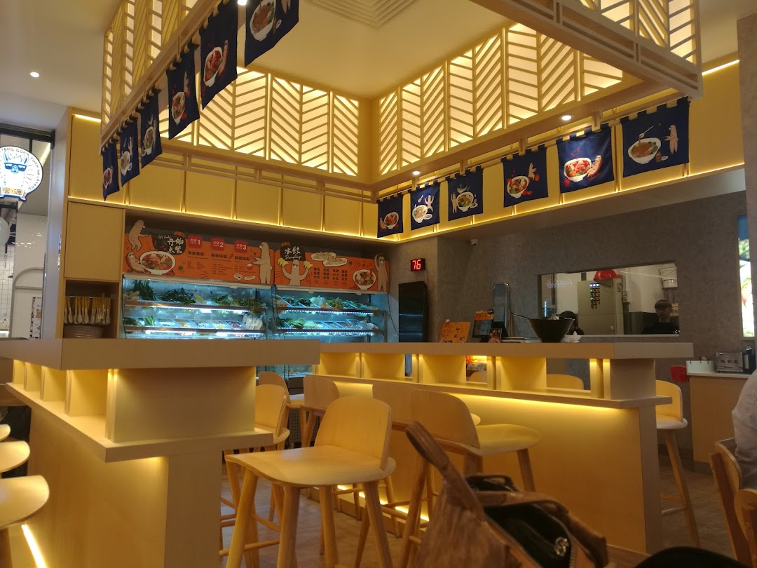 Interior view of Gong Yuan Ma La Tang, featuring a bright, modern counter with ingredient displays and bar seating.